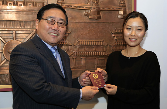 中国驻悉尼总领事李华新为第一位领取电子护照的申请人颁发新护照（摄影 贺吉）