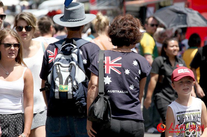 身穿国旗服装的澳人夫妇穿过街头熙熙攘攘的人群（摄影 马小龙）