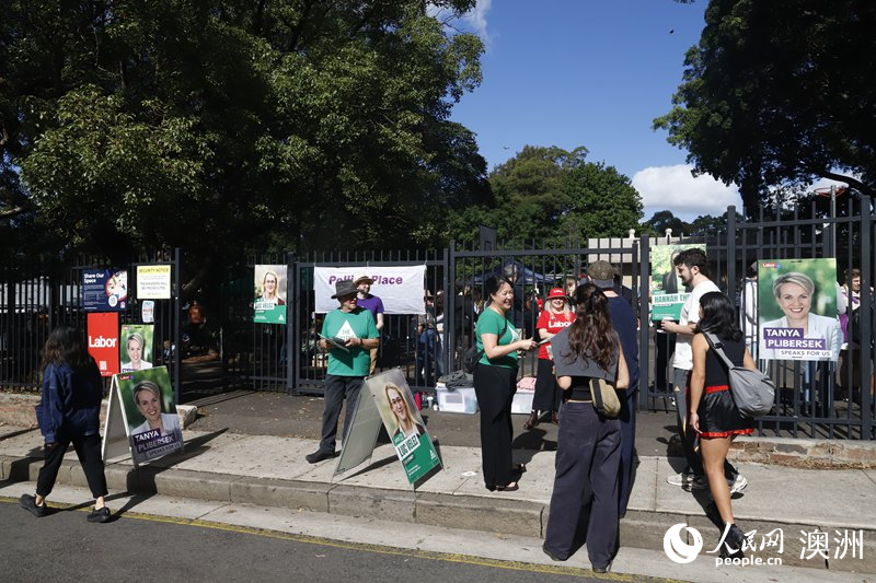 志愿者在投票站外向选民分发宣传单（摄影 刘美鹭）
