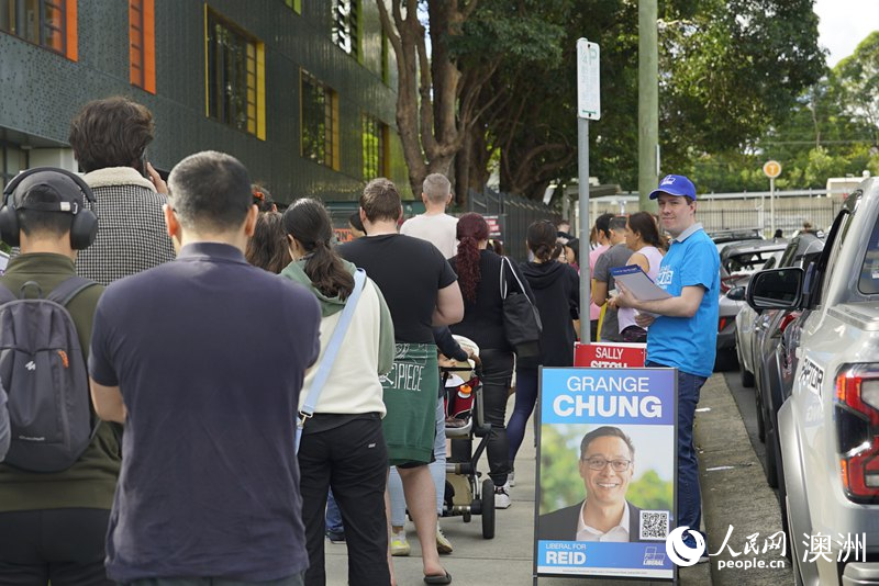 志愿者在投票站外向选民分发宣传单（摄影 杨怡筠）