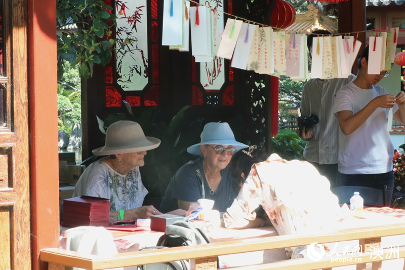 来自黄金海岸的苏珊（左一）和妹妹在游园会现场体验书法活动（摄影 王泉骄）