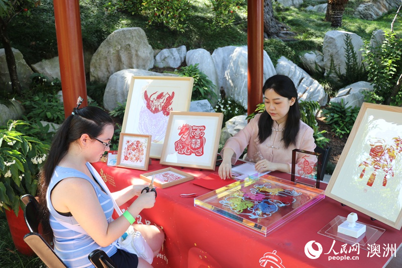 游客在游园会现场体验剪纸（摄影 王泉骄）