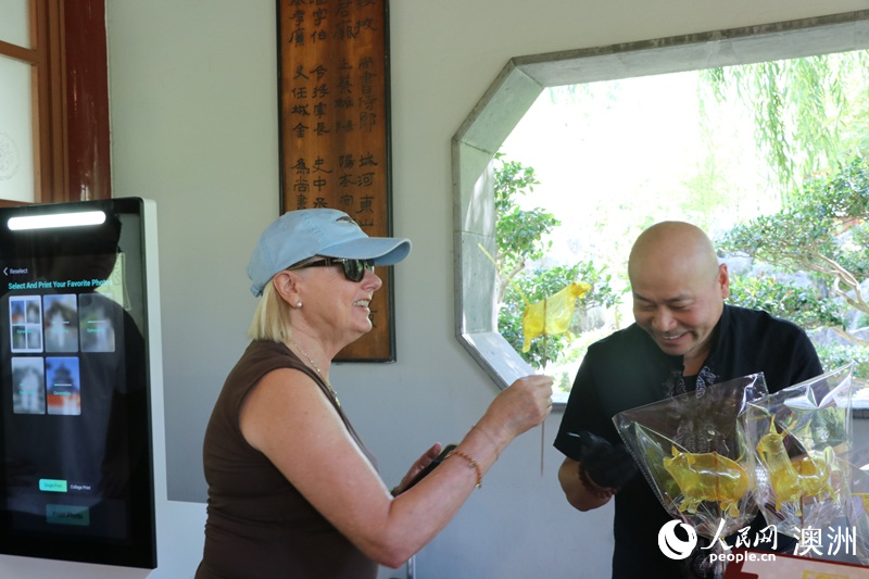 游客在游园会现场体验吹糖人（摄影 王泉骄）